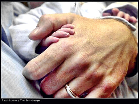 A father holds his baby's hand in his