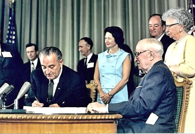 President Johnson signs Medicare law - President Truman looks on